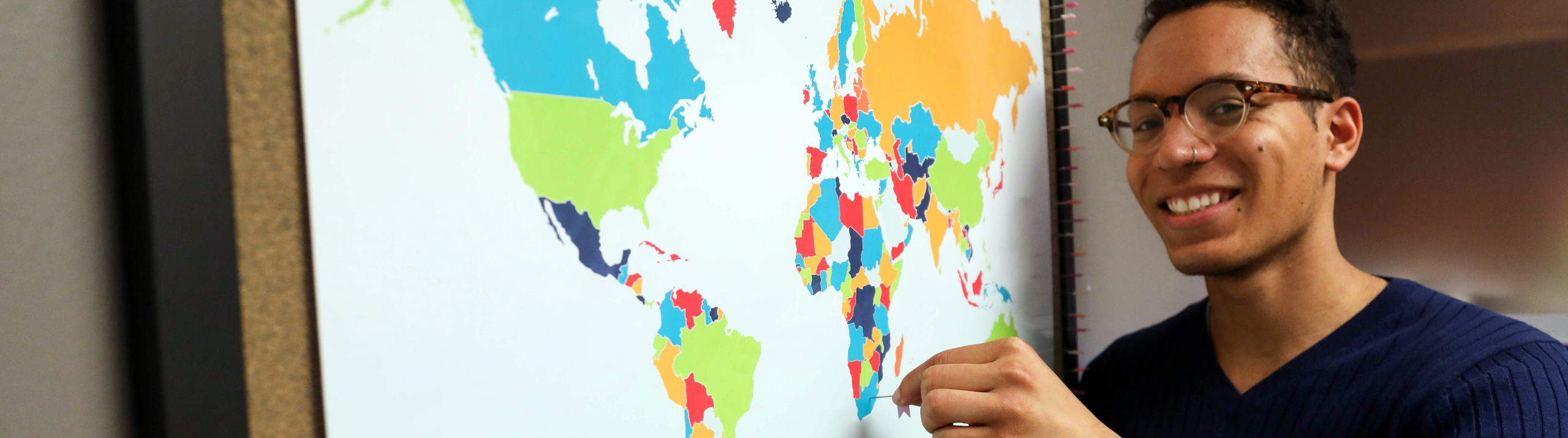 Honors College student standing in front of the world map with pins
