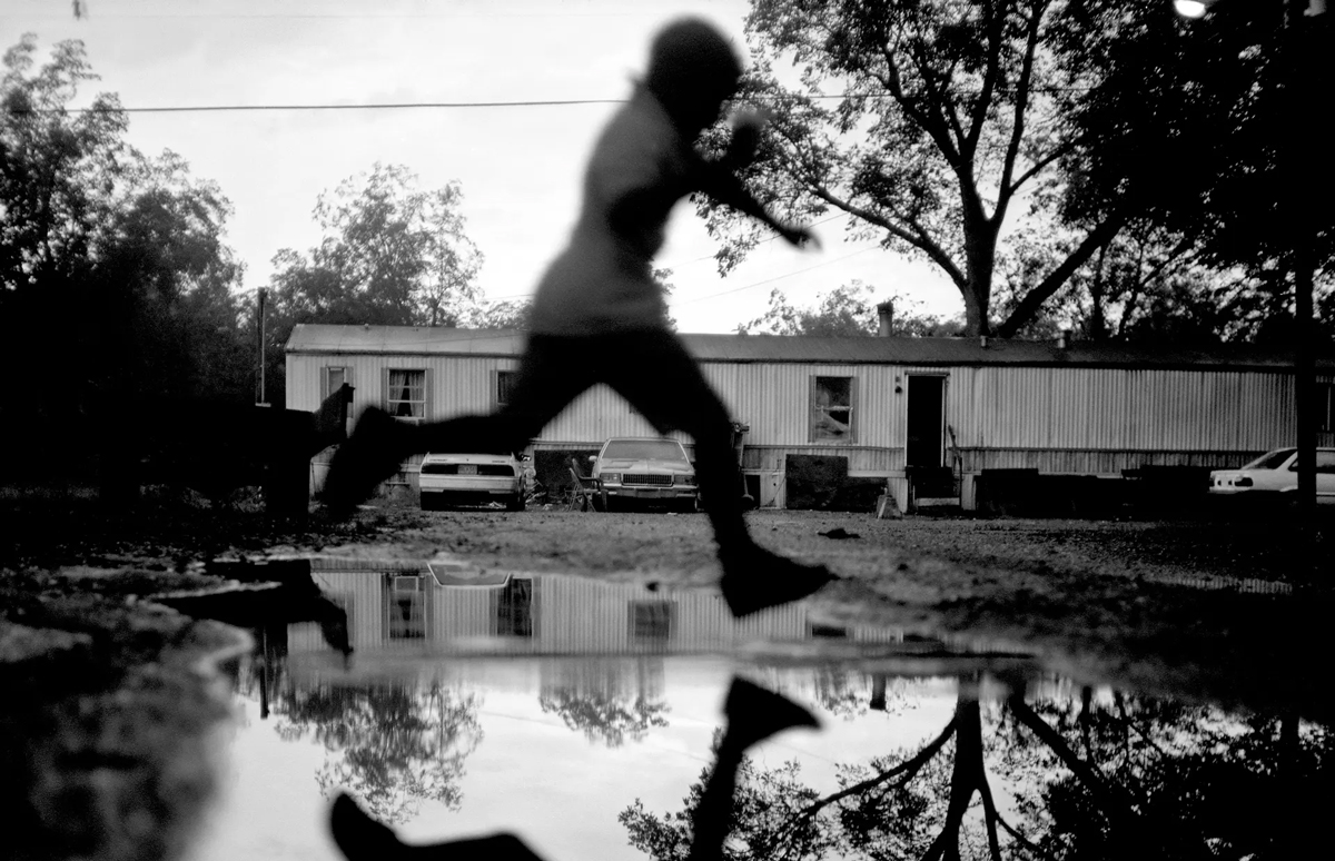 A young boy jumps over a water puddle in front of the Coffey residence after a rainstorm in Duncan, September 2009, Photo by Brandon Thibodeaux, THEGUARDIAN.COM