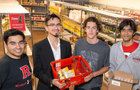 A photo of students Hassan Choudhry, Steven Montes Montecinos, Jonathan Shoham, and Thirth Patel holding baskets of food at the Rutgers Food Panty.