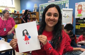 Aneesha holding a picture she drew with a child