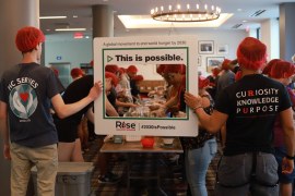 Students packaging meals and holding a sign that says, "This is Possible" referencing ending hunger by 2030