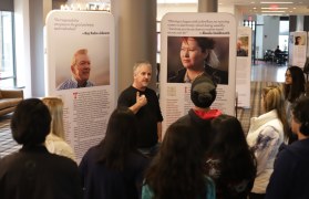 John Noltner standing in front of his exhibit talking with students