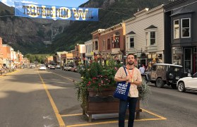 Student standing on street in Telluride with film festival banner behind